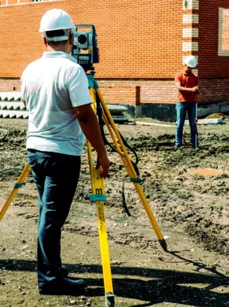 Салафан ішіндегі геодезиялық құралды әріптестерімен бірге қолданатын маман