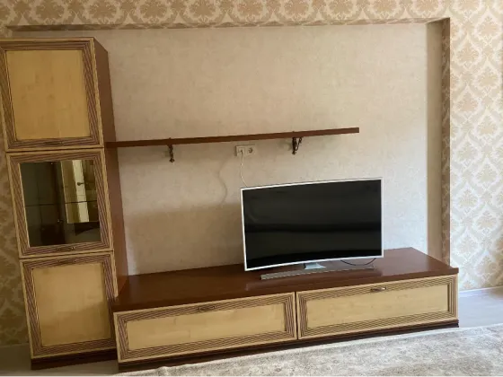 Телевизионный стенд с витриной и полкой для телевизора на фоне обоев