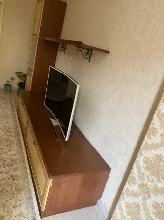 Вид телевизионного стенда сбоку с телевизором и полкой для декора