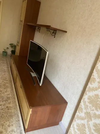 Вид телевизионного стенда сбоку с телевизором и полкой для декора