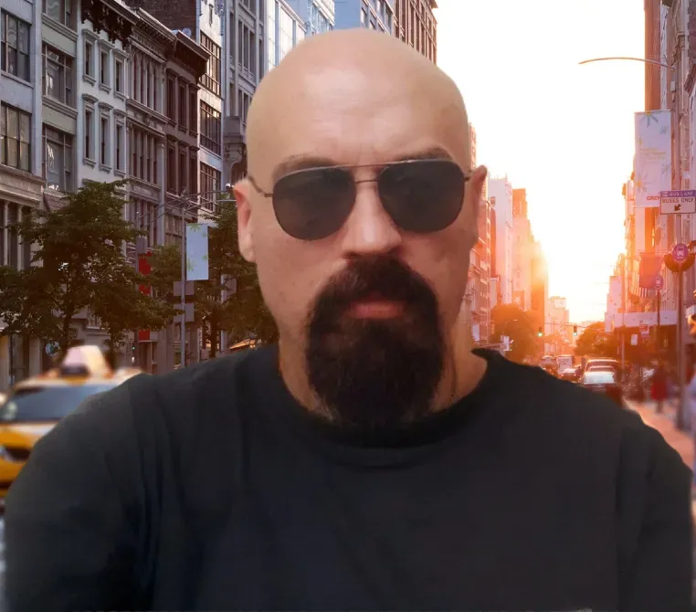 Неизвестный человек в черной футболке и темных очках на фоне городского пейзажа с закатом