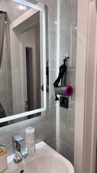 зеркало и фен на стене ванной комнаты