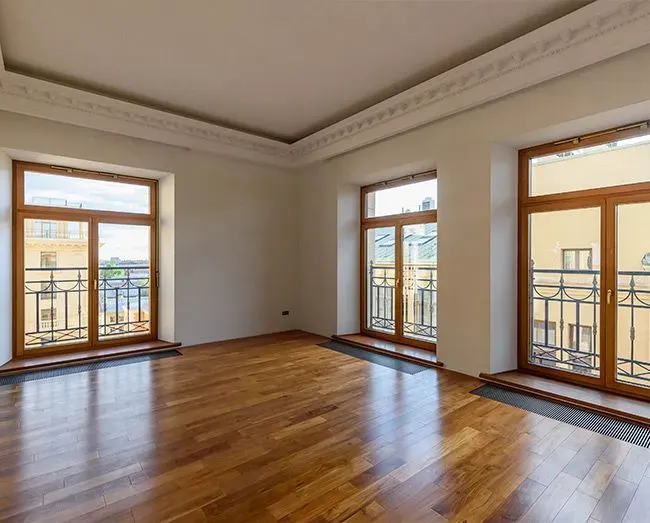 Үлкен терезелері және ағаш едені бар кең бөлме