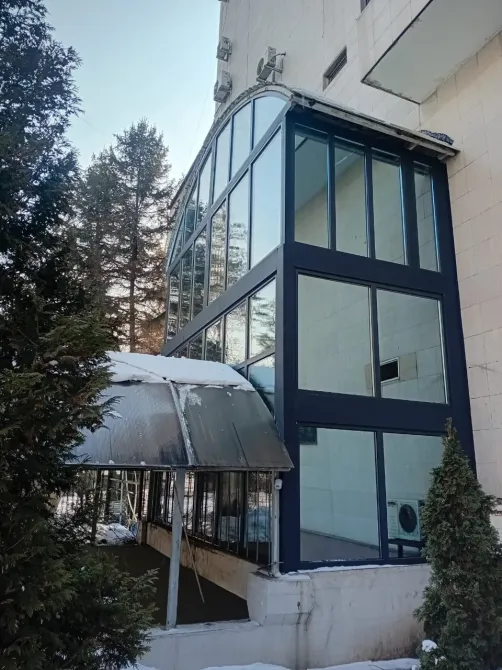 Қызықты ландшафтпен үлкен шыны терезелері бар заманауи үй