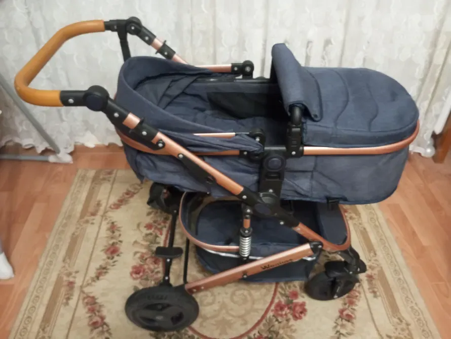 Коляска с темно-синим текстилем и золотистыми элементами, вид сбоку