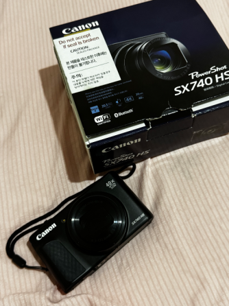 Canon камерасы PowerShot SX740 HS қорабының жанында матада