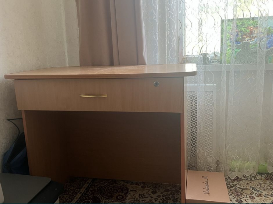 Стол с одним ящиком и золотой ручкой, рядом с окном и занавеской