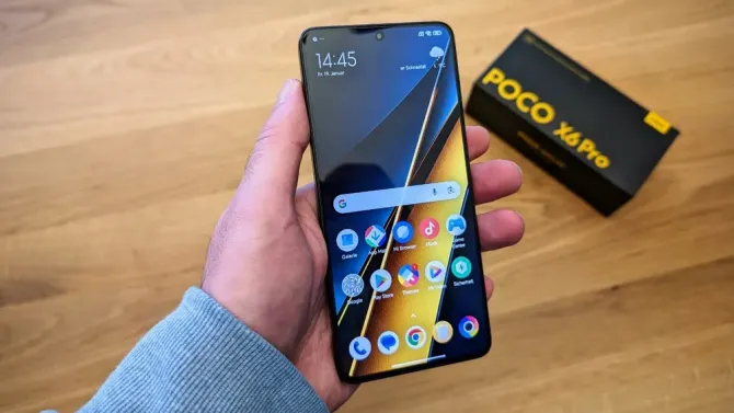 Смартфон Poco X6 Pro в руке с коробкой на фоне