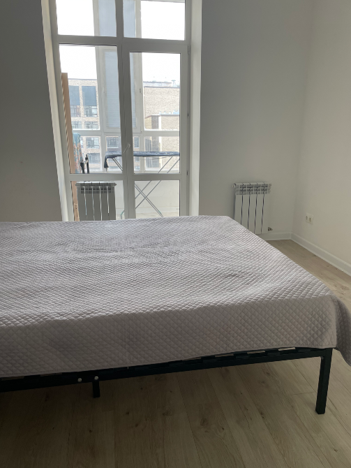 үлкен терезе мен кереуеті бар жайлы жатын бөлме