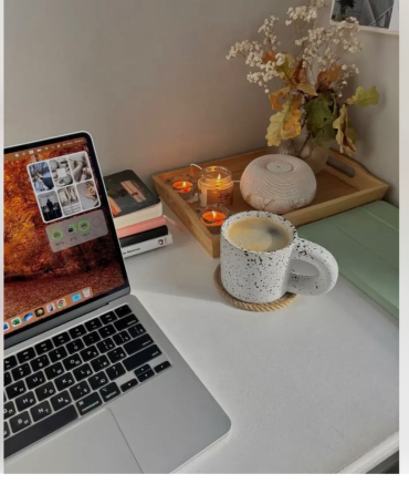 Стильное рабочее место с MacBook, кружкой кофе, свечами и декоративными элементами