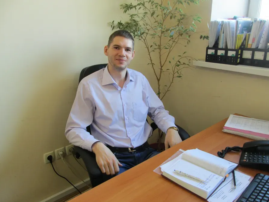 Человек в красной футболке стоит перед светящейся стеной из огней