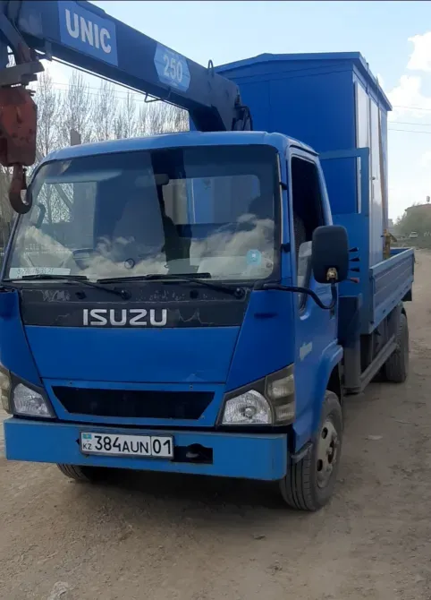 Грузовик Isuzu с подъемным краном на фоне деревенской местности