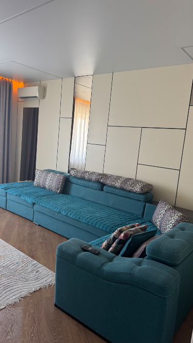 Современная гостиная с синем диваном и уютными подушками, стильный интерьер, светлые тона, деревянный пол