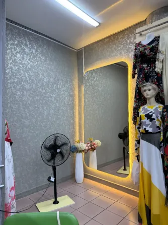 Интерьер бутика с зеркалом и одеждой на манекенах