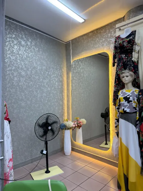 Интерьер бутика с зеркалом и одеждой на манекенах