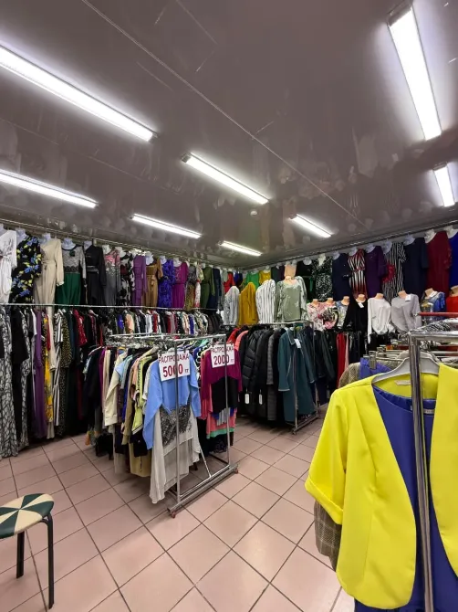 Просторный магазин с яркими платьями и футболками на вешалках