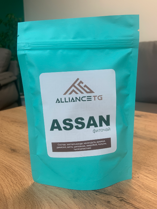 Alliance TG компаниясының ASSAN фиточайының упаковкасы ағаш бетінде