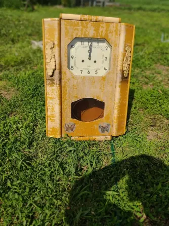 Деревянные настенные часы с круглым циферблатом на фоне зелёной травы