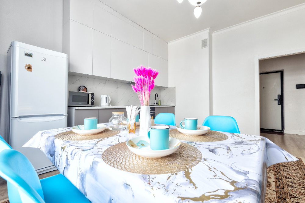 Кухня со столом, стульями и холодильником, оформленная в светлых тонах