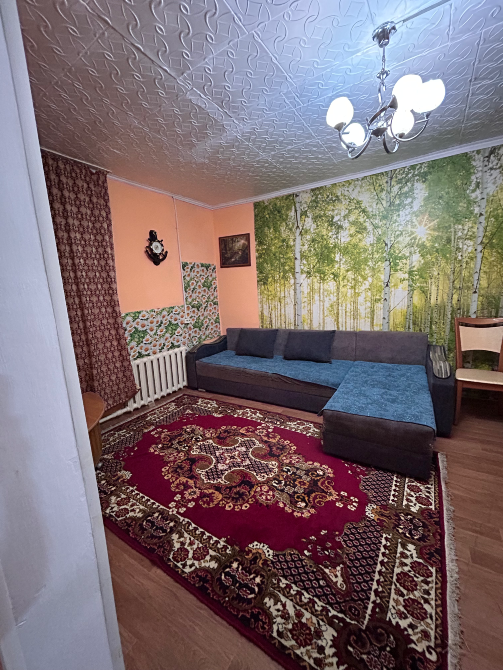 Диван мен қабырға қағазымен жабылған қонақ бөлмесі