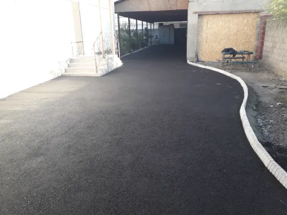 Новое асфальтное покрытие во дворе частного дома с цветами и забором