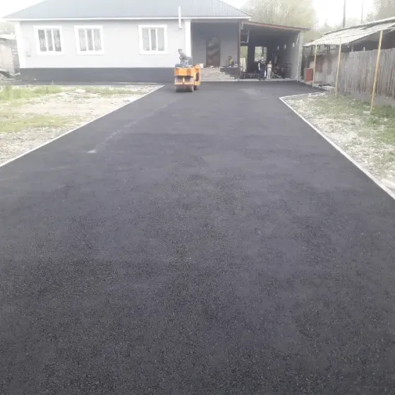 Новое асфальтное покрытие во дворе частного дома с цветами и забором