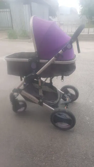 Детская коляска с фиолетовым капором и черной корзиной на колесах