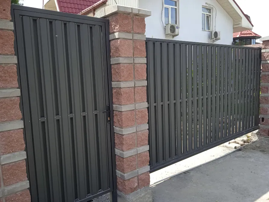 Тастан жасалған бағандар арасында тік планкалармен қоршалған есік