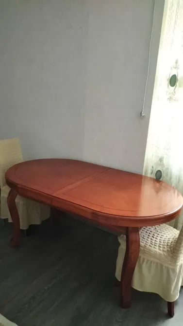 Ағаштан жасалған жұмыртқа тәрізді үстел, ою-өрнекпен безендірілген аяғымен интерьерде, екі жұмсақ жастықпен жабдықталған орындықтар.