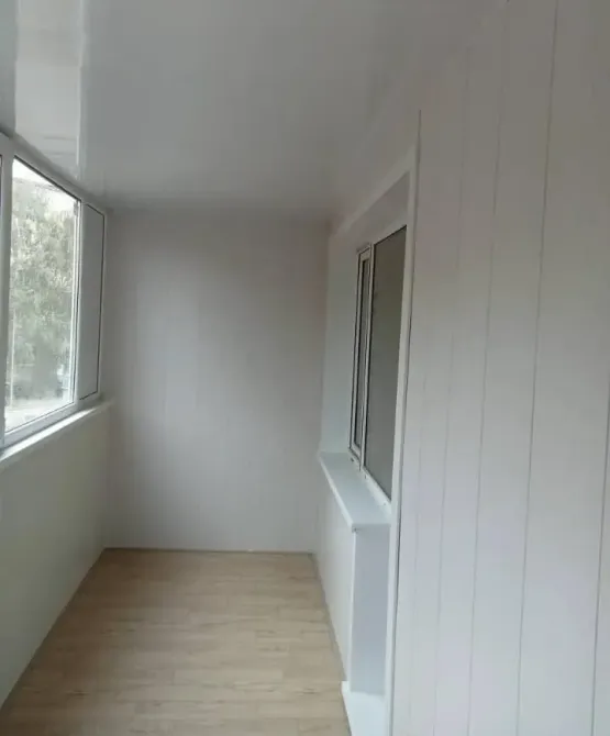 Застекленная лоджия с деревянным полом и белыми стенами