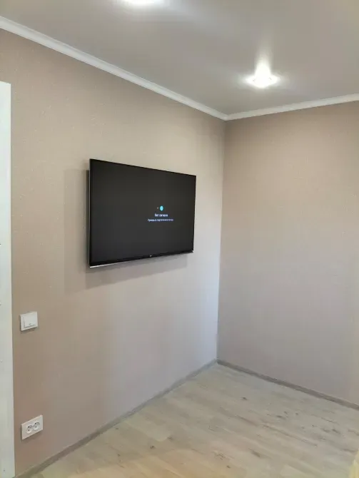 Гостиная с настенным телевизором на фоне нейтральной стены