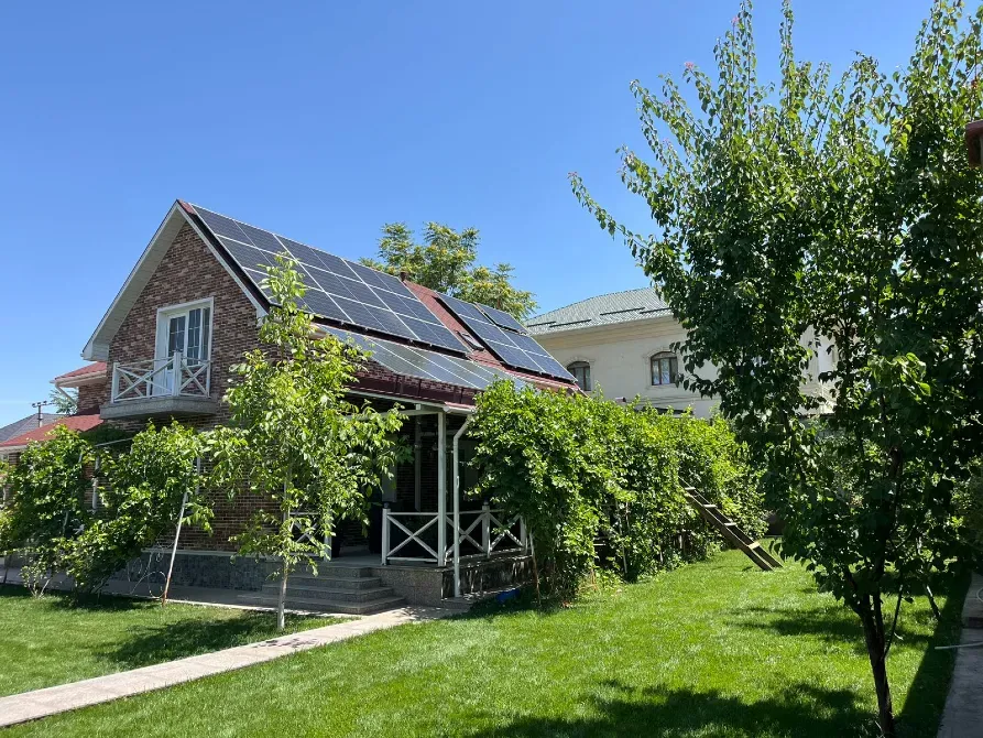 Күн панельдері бар үй мен күтімді газон көрінісі