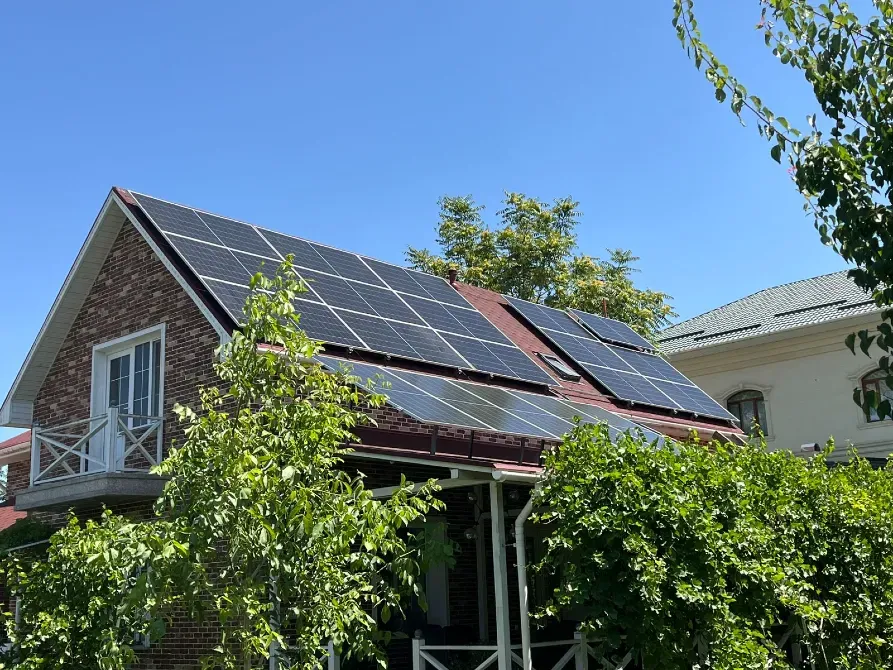 Жасылмен қоршалған үйдің крышадағы күн панельдері