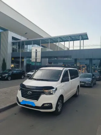 Белый минивэн Hyundai на фоне здания аэропорта