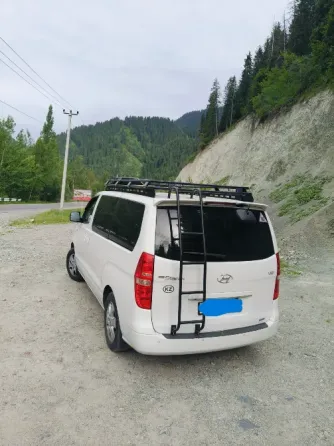 Белый минивэн Hyundai на фоне здания аэропорта