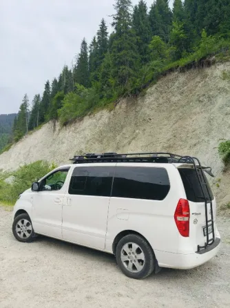 Белый минивэн Hyundai на фоне здания аэропорта