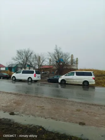 Белый минивэн на мокрой дороге с деревьями на заднем плане