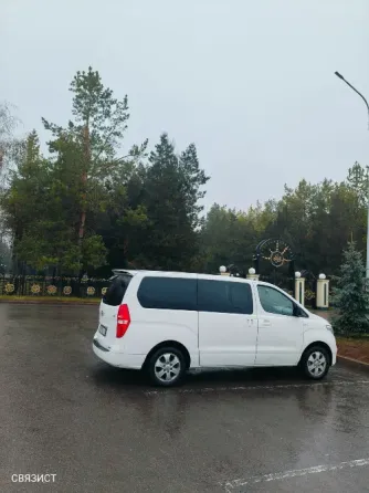 Белый минивэн на мокрой дороге с деревьями на заднем плане