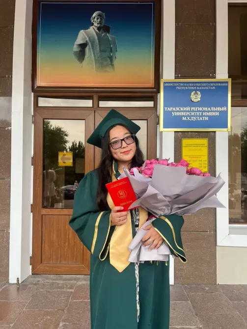 Дипломмен және гүл шоғымен академиялық атрибутикадағы түлек