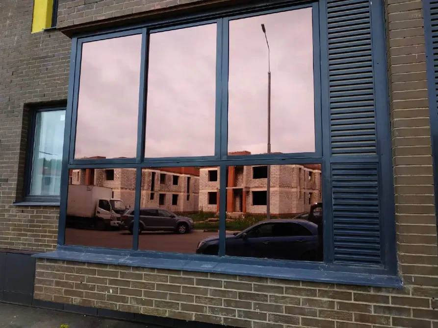 Көшедегі салынып жатқан ғимараттардың көрінісі бар шыны терезелер