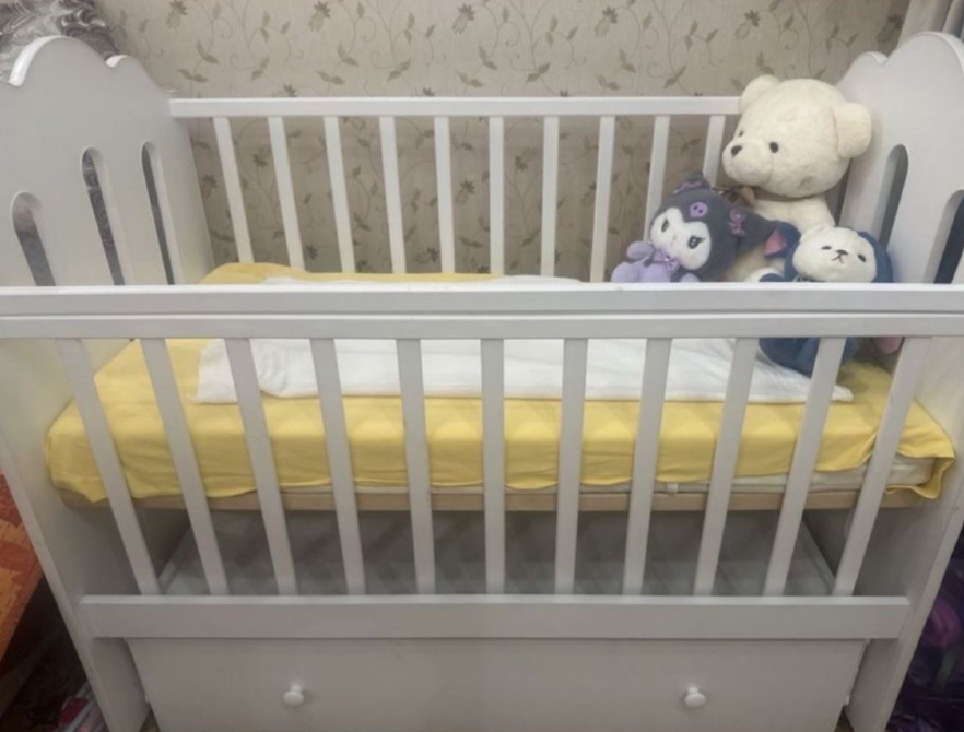 Кроватка для новорожденных с желтым матрасом и мягкими игрушками на одеяле