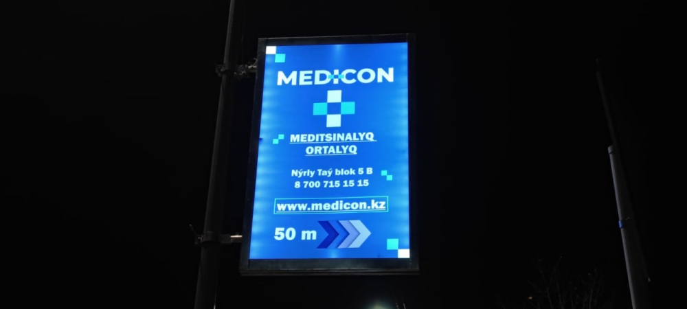Түнгі уақытта жарықшам опорында медициналық орталықтың жарқын жарнамасы