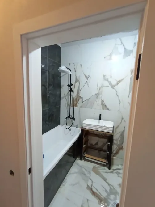 Стильді ванна бөлмесі ваннамен және қабырғаларында әсерлі плиткамен