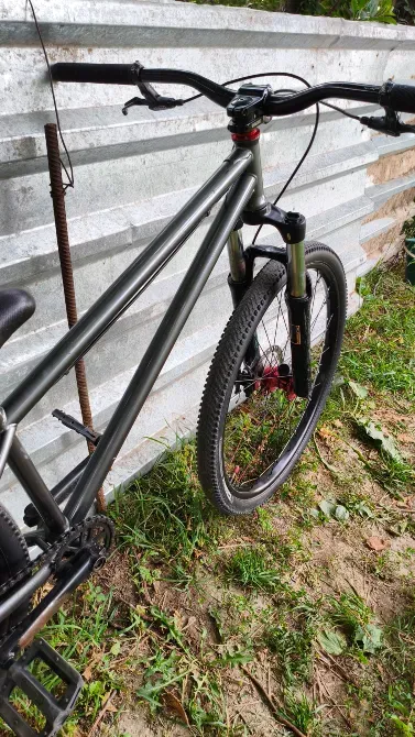 Қара жақтаулы велосипед металл қабырғасының фонында