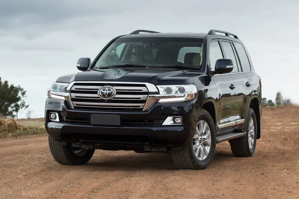 Қара Toyota Land Cruiser жолсыз жерде, балшықты жолда және бұлтты аспанда.