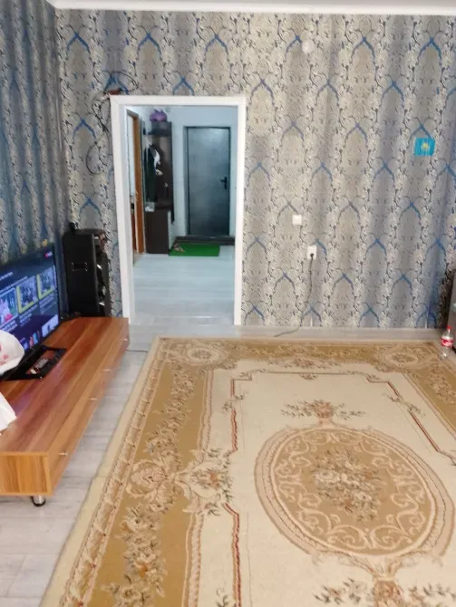 интерьер комнаты с телевизором, диваном и светлыми обоями