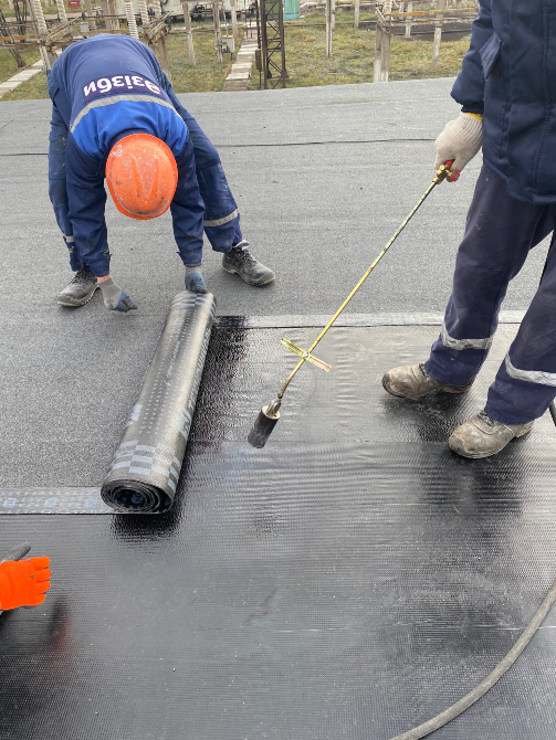 Шатырда рулонды материалды төсеуші жұмысшылар, біреуінде газ оттық құрылғысы бар