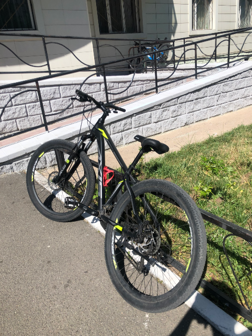 қара рамалы велосипед және қызыл бөтелке ұстағышы үйдің жанында