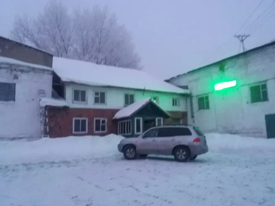 Заброшенное здание в снегу с автомобилем на переднем плане