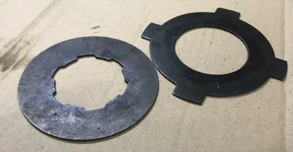 Детали механизма, черные круглые прокладки различной формы, показанные на картонной поверхности